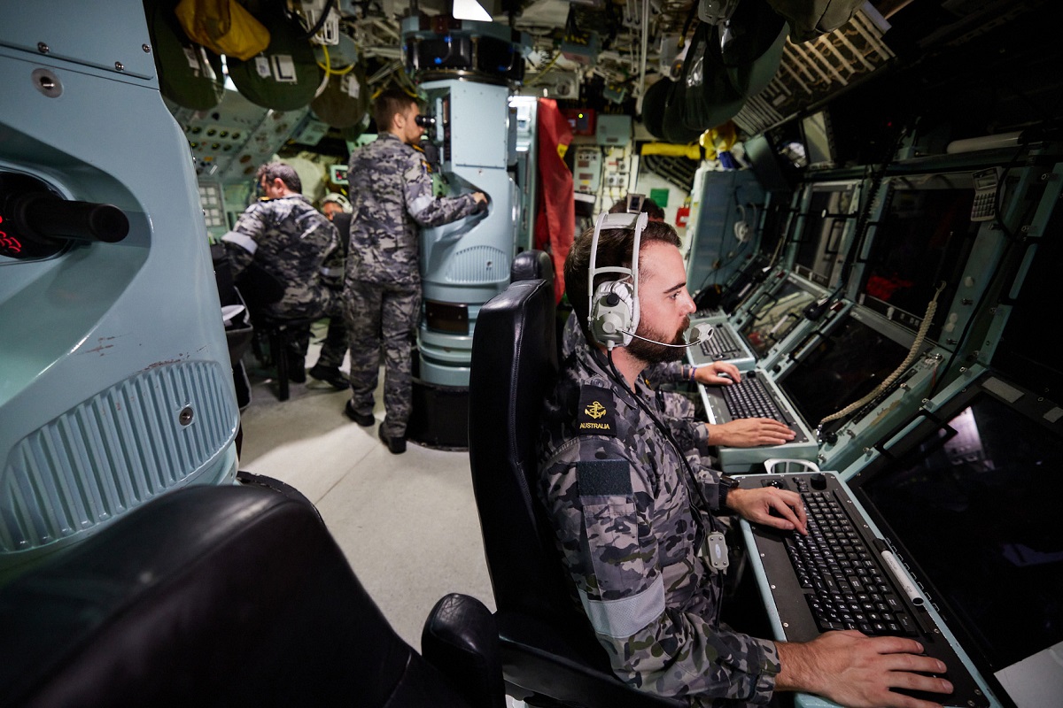 Officers and Sailors inside a Collins-class submarine control room conducting operations at periscope depth.