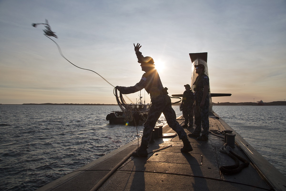 Able Seaman Acoustic Warfare Analyst Submariner Liam Shelley throws a heaving line to a tug boat as HMAS Waller prepares to come alongside Fleet Base West.