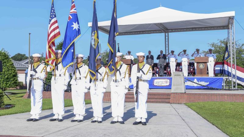 US Navy Sailors holding United States and Australian flags at graduation ceremony of US Navy's Nuclear Power School.