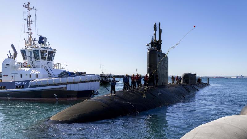 A crew member of the United States Navy Virginia-class submarine USS North Carolina (SSN 777) throws a line ashore as the submarine arrives at Fleet Base West, Rockingham, Western Australia.