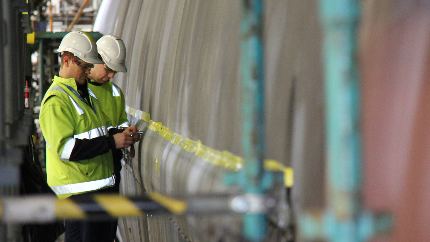 Two people helmets and hi-vis jackets looking a the side of submarine